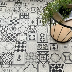 Curiosity vinyl flooring in monochrome patchwork tile, with a rattan chair and plant