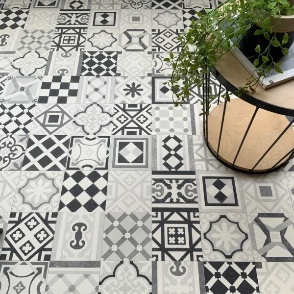 Curiosity vinyl flooring in monochrome patchwork tile, with a rattan chair and plant