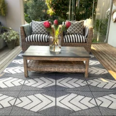 Mountains Grey outdoor rug on a patio beneath a bench with striped cushions