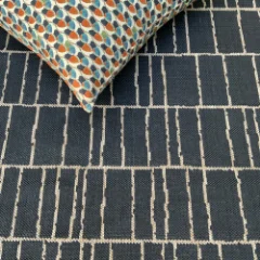 Corner of a dark Stacks rug turned back to show its patterned reverse