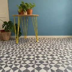 Gallery vinyl flooring in a grey geometric tile pattern, with a yellow hairpin table against a teal wall