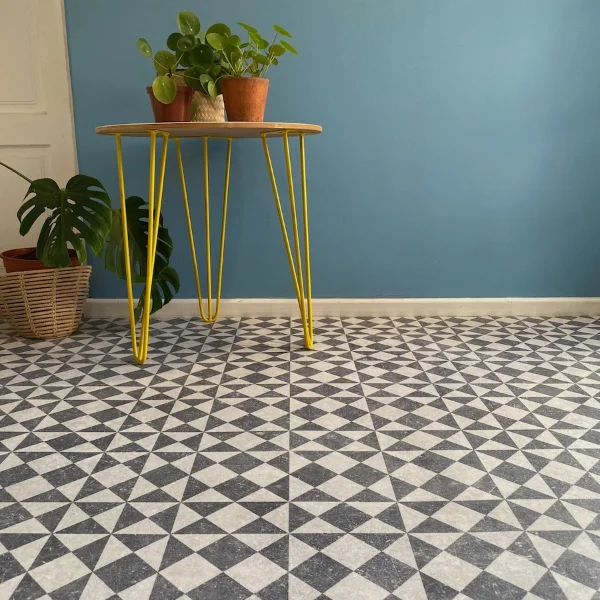 Gallery vinyl flooring in a grey geometric tile pattern, with a yellow hairpin table against a teal wall