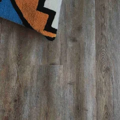 Amatola vinyl plank flooring in mid grey, with the corner of a boldly patterned rug