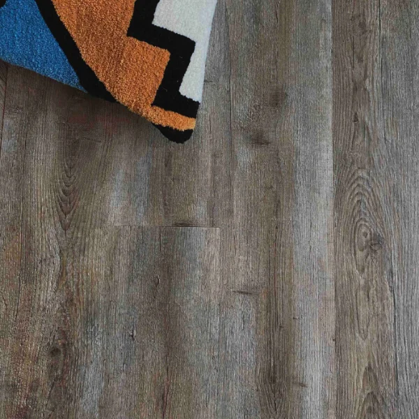 Amatola vinyl plank flooring in mid grey, with the corner of a boldly patterned rug