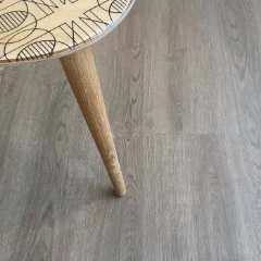 Cradle Moon vinyl plank flooring in grey, beneath a tapered timber furniture leg and a patterned rug