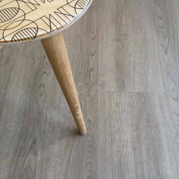 Cradle Moon vinyl plank flooring in grey, beneath a tapered timber furniture leg and a patterned rug
