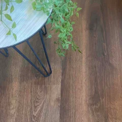 Otter vinyl plank flooring in dark walnut brown, with a blue plant stand and green foliage