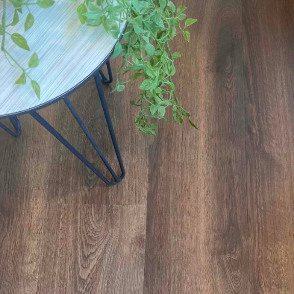 Otter vinyl plank flooring in dark walnut brown, with a blue plant stand and green foliage