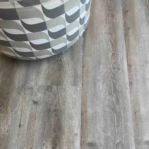 Outeniqua vinyl plank flooring in cool mid grey, with a white faceted vessel in one corner