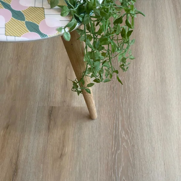 Platteklip vinyl plank flooring in pale grey, beneath a timber-legged stool and a trailing plant