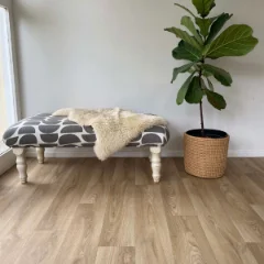 Solace vinyl flooring beneath a sheepskin-topped bench and a fiddle-leaf fig in a basket