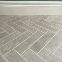 Close-up of Klompie herringbone brick vinyl flooring against white skirting