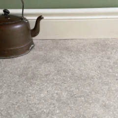 Close-up of SunStone honed-stone vinyl flooring beside a copper kettle
