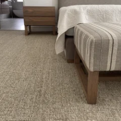 Sisal Linen carpet fitted in a bedroom beside a bed with a folded throw