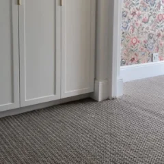Veld Knotted Pewter carpet fitted on a landing with white panelled doors and floral wallpaper
